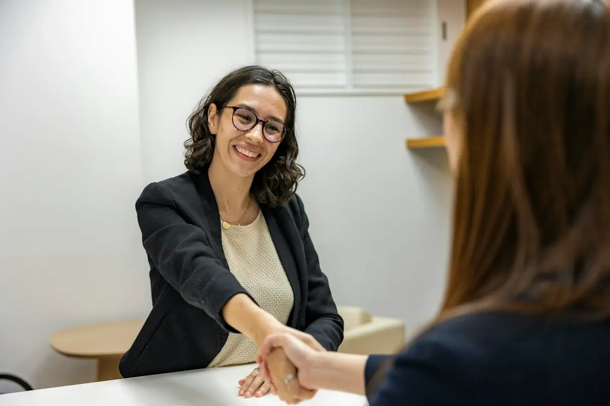 Una reclutadora saluda a una candidata al iniciar una entrevista.
